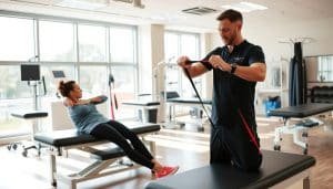 A well-equipped sports therapy clinic, showcasing a patient undergoing a comprehensive rehabilitation protocol. In the foreground, a physiotherapist guides the athlete through a series of gentle exercises, utilizing resistance bands and other specialized equipment. The middle ground features state-of-the-art treatment tables and medical devices, conveying the advanced nature of the facility. In the background, large windows flood the space with natural light, creating a warm and inviting atmosphere. The overall scene exudes professionalism, expertise, and a commitment to the athlete's recovery and well-being.